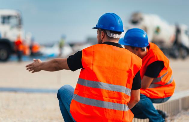 Two transport workers on a construction site with helmet and safety jacket